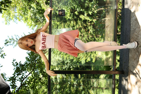 Full-length view of Iris standing outdoors in a pink skirt