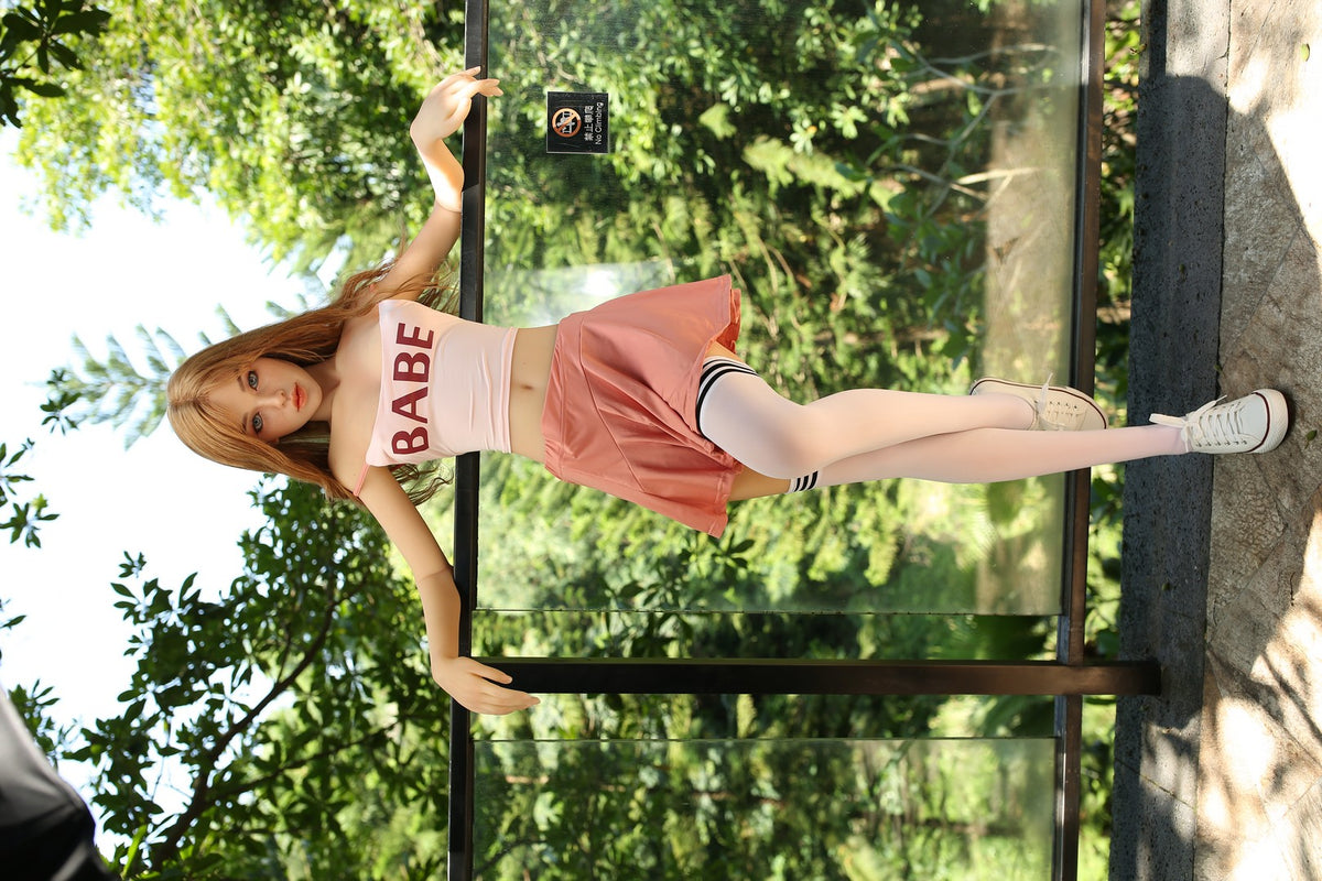 Full-length view of Iris standing outdoors in a pink skirt