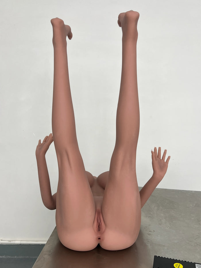 Full-body product view of the silicone doll in a raised-leg pose, showing flexible positioning, sculpted legs, and realistic silicone detailing.