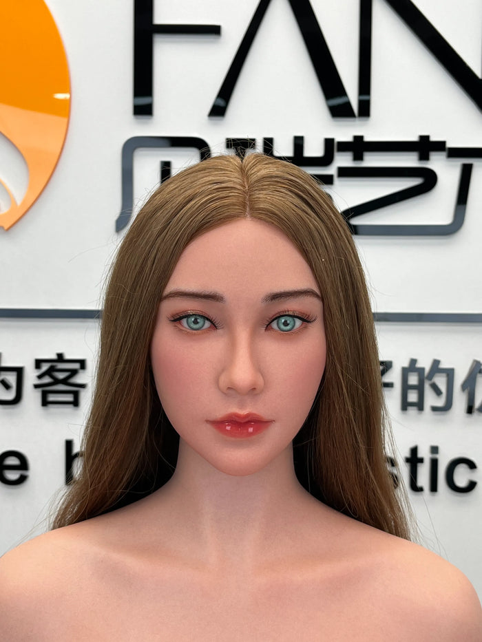 A hyper-realistic silicone female doll, featuring long light-brown hair, blue eyes, and pink lips; showcasing the head sculpt and makeup.